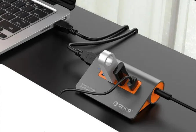 Dark grey USB-C laptop hub with four orange-accented USB 3.1 ports and separate data cable