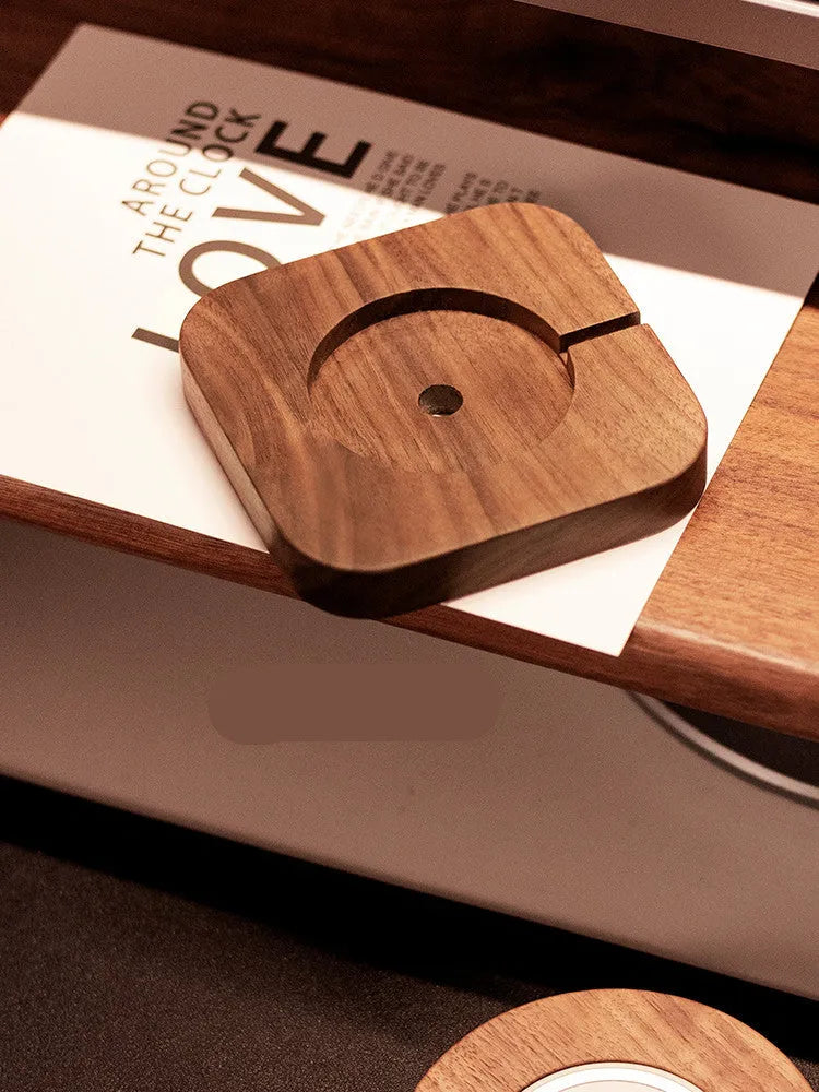 Solid walnut wood magnetic wireless charging bracket base for Magsafe iPhones on a desktop.