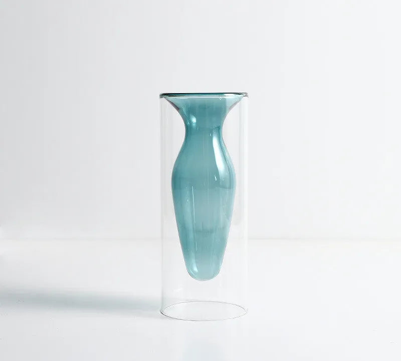 Colourful double layer blown glass vase in pink tone on a dining table with dried flowers
