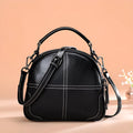 Round leather handbag with dual soft handles in wine red colour, showing zipper closure and compact shape.