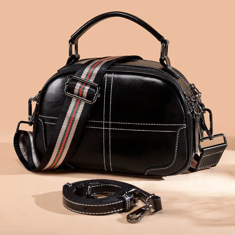 Round leather handbag with dual soft handles in wine red colour, showing zipper closure and compact shape.