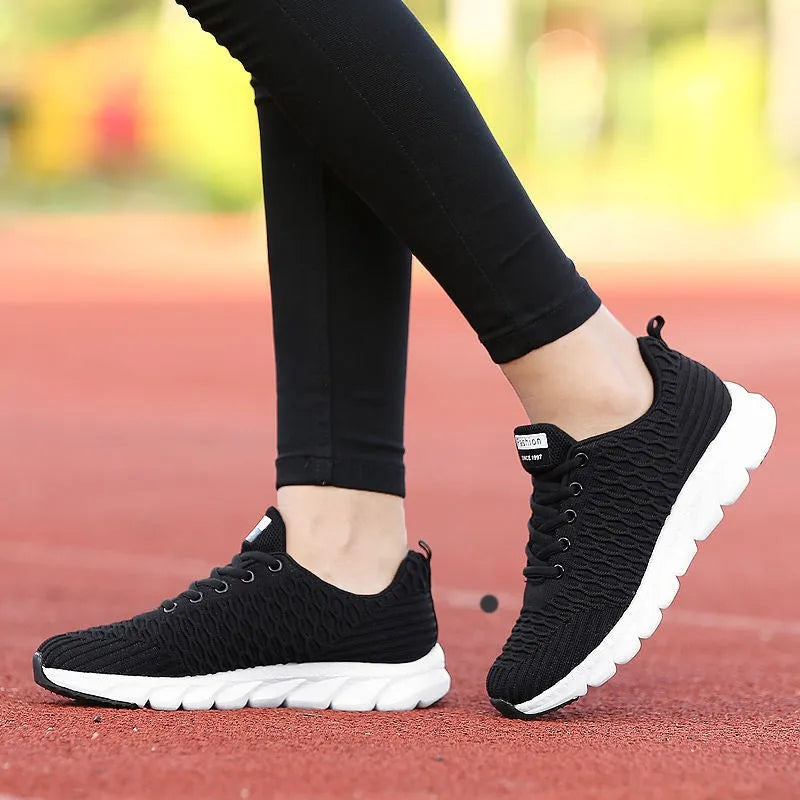 Women's fly knit running shoes in black, pink, or white colours, showing the woven upper and durable outsole.