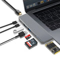 Silver USB-C multi-port hub for MacBook Pro with eight interface ports including USB, card slots, and display output