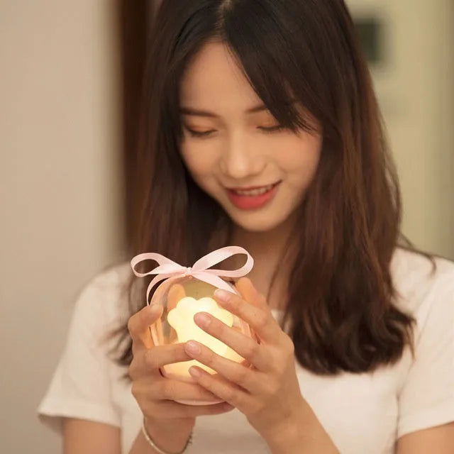 Grey or pink cat paw shaped USB rechargeable night light with music box function on a desk.