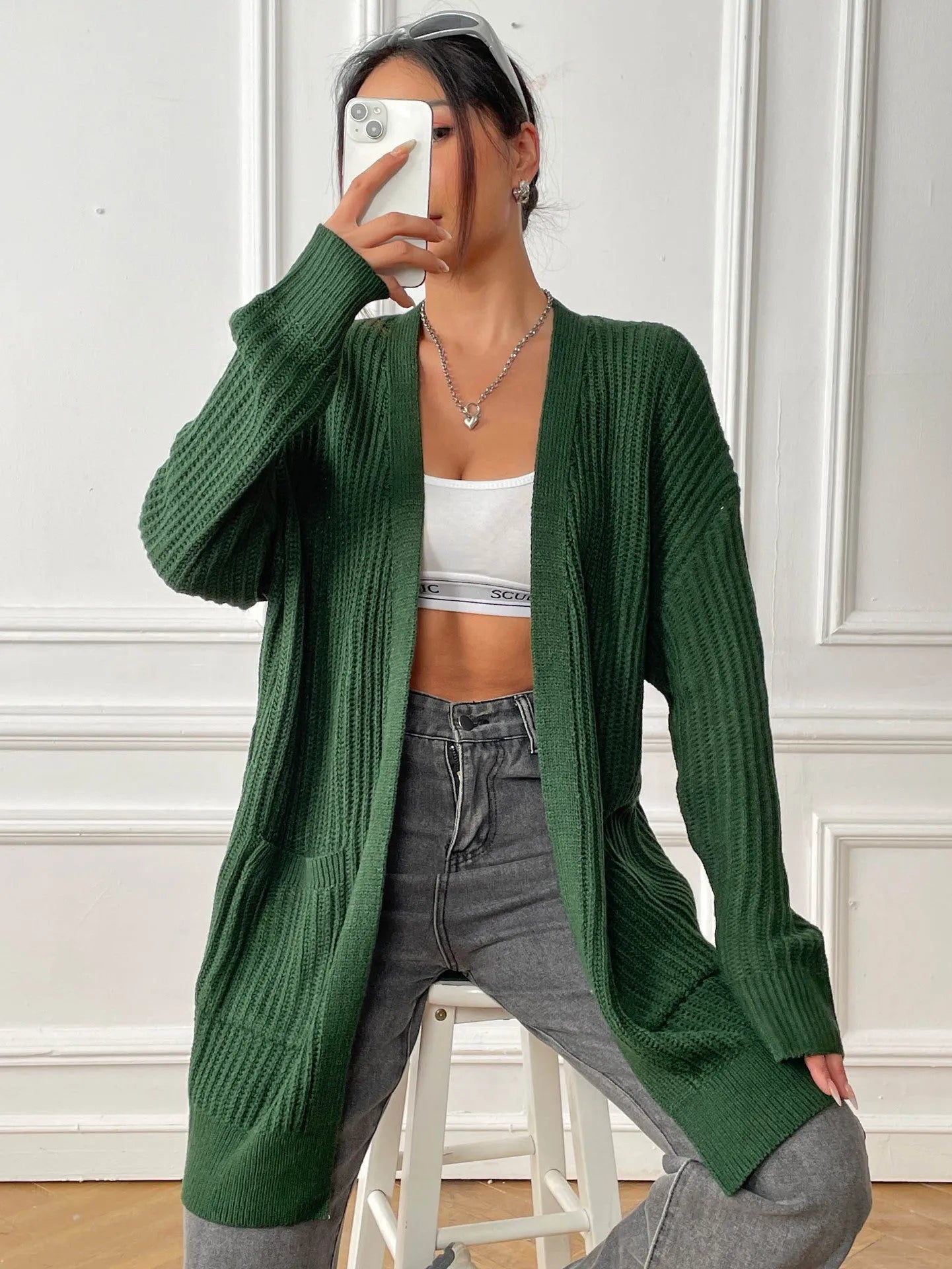 Women's dark green two-pocket acrylic cardigan sweater with loose fit and long sleeves
