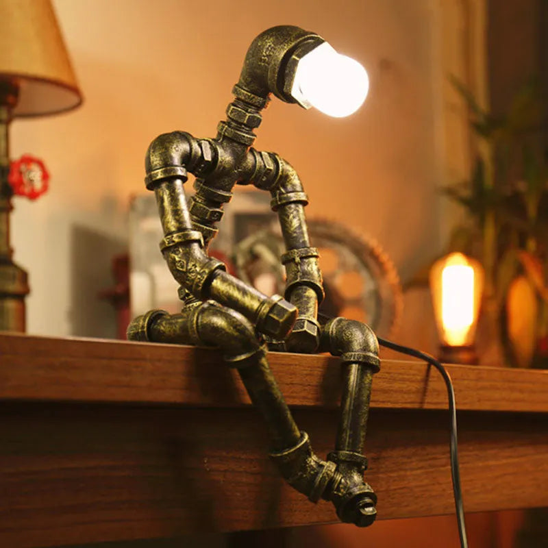 Green bronze vintage robot table lamp with industrial iron pipe design on wooden desk