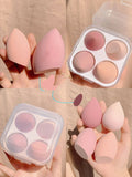 Cube-shaped plastic makeup sponge storage case containing four coloured synthetic beauty egg sponges.