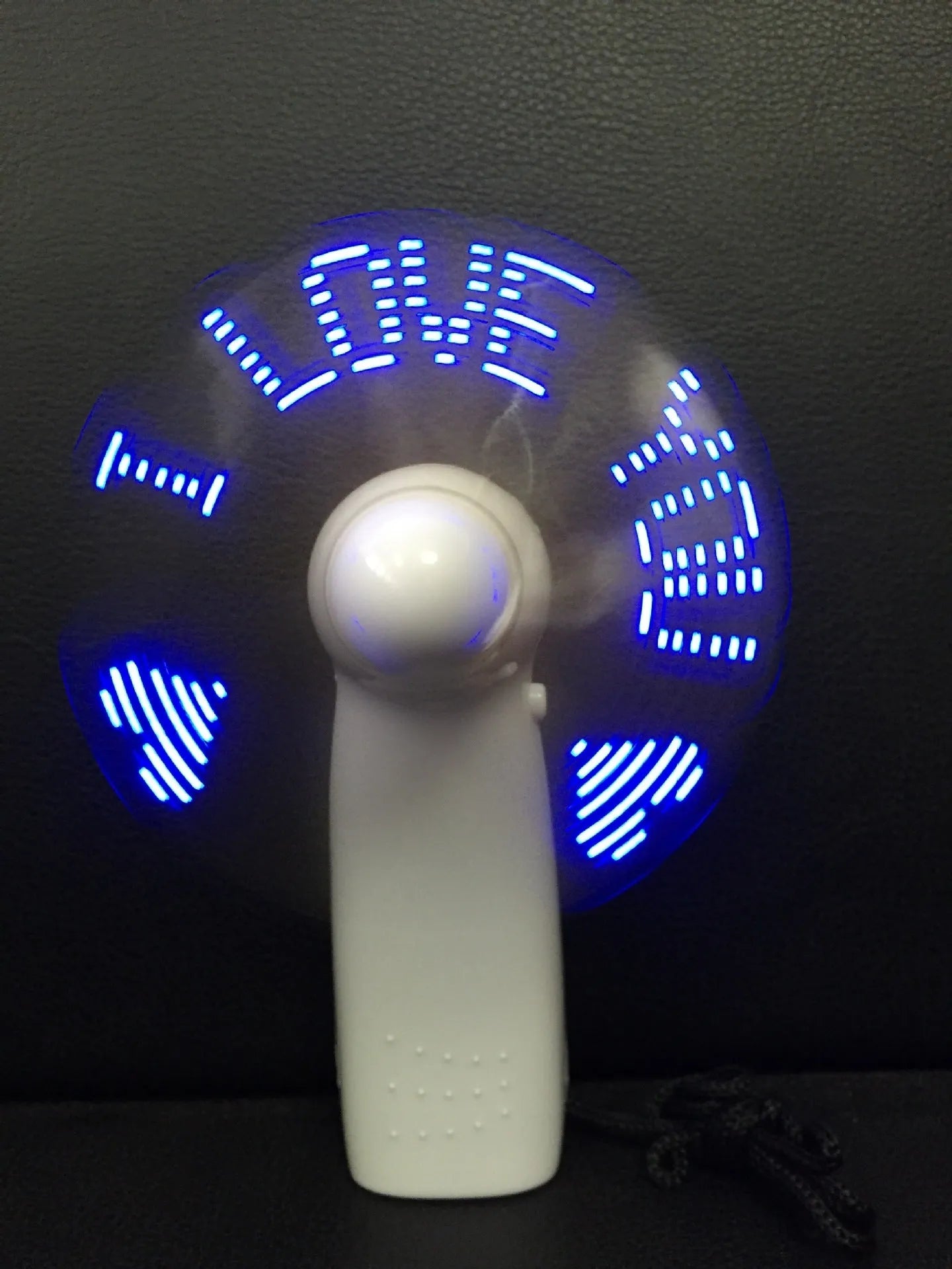 White handheld mini fan with blue and red LED lights flashing a love message pattern