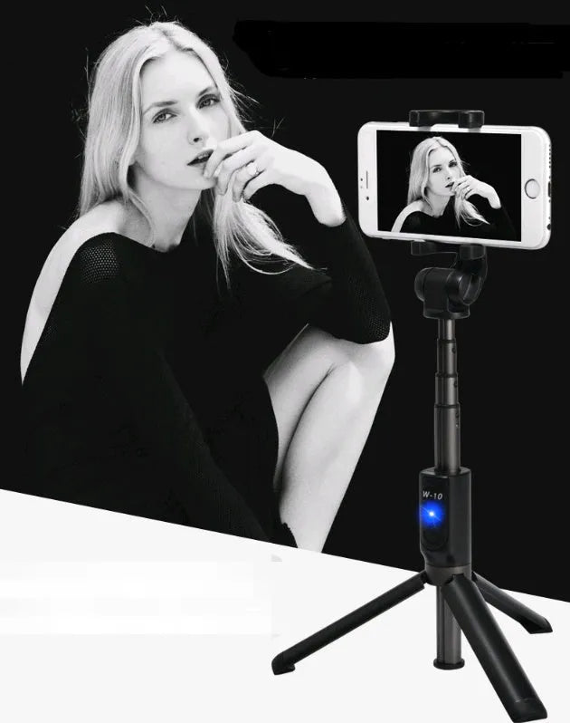 Aluminium Bluetooth selfie stick with tripod base and remote control next to a mobile phone.