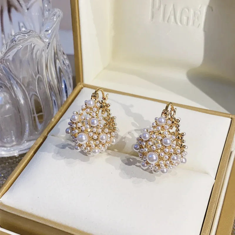 Gold-coloured copper flower basket earrings with small rice-shaped bead inlay detail.