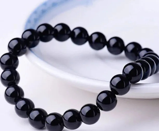 A geometric black onyx bracelet for women with 8mm beads on an elastic cord.