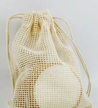 Set of eight pink and blue velvet makeup remover pads next to an organic cotton mesh drawstring bag.