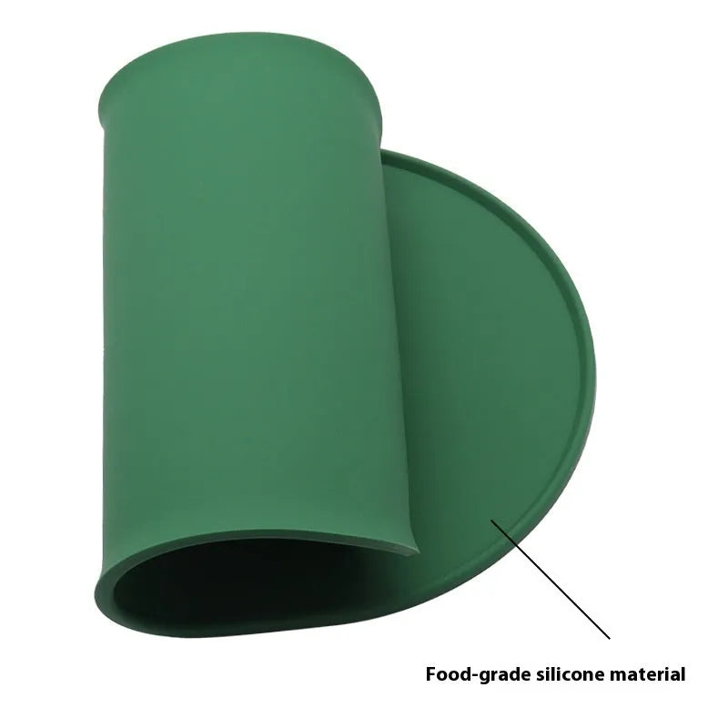 Silicone cat feeding placemat in green colour, shown under a food bowl on a wooden floor.