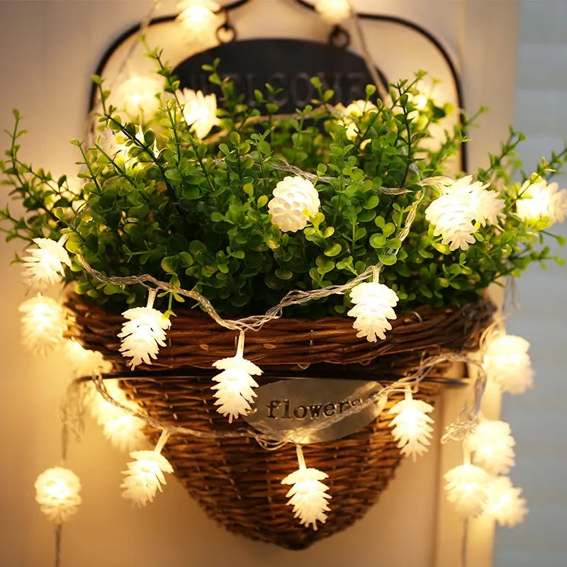 Battery-powered warm white LED pine cone light string with plastic shells, shown in 10 or 20 light options.