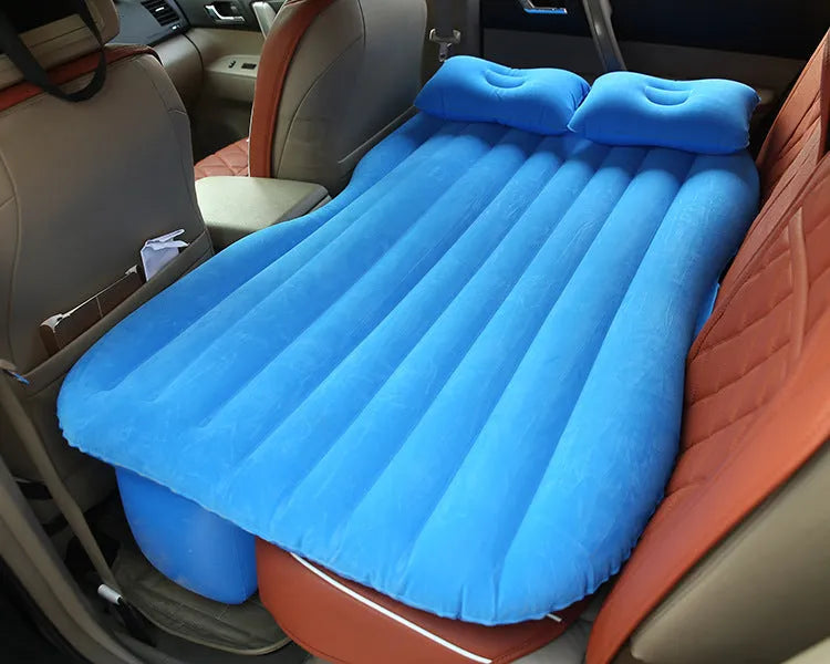 Inflatable car bed with flocked surface and two pillows, shown folded next to its storage bag.