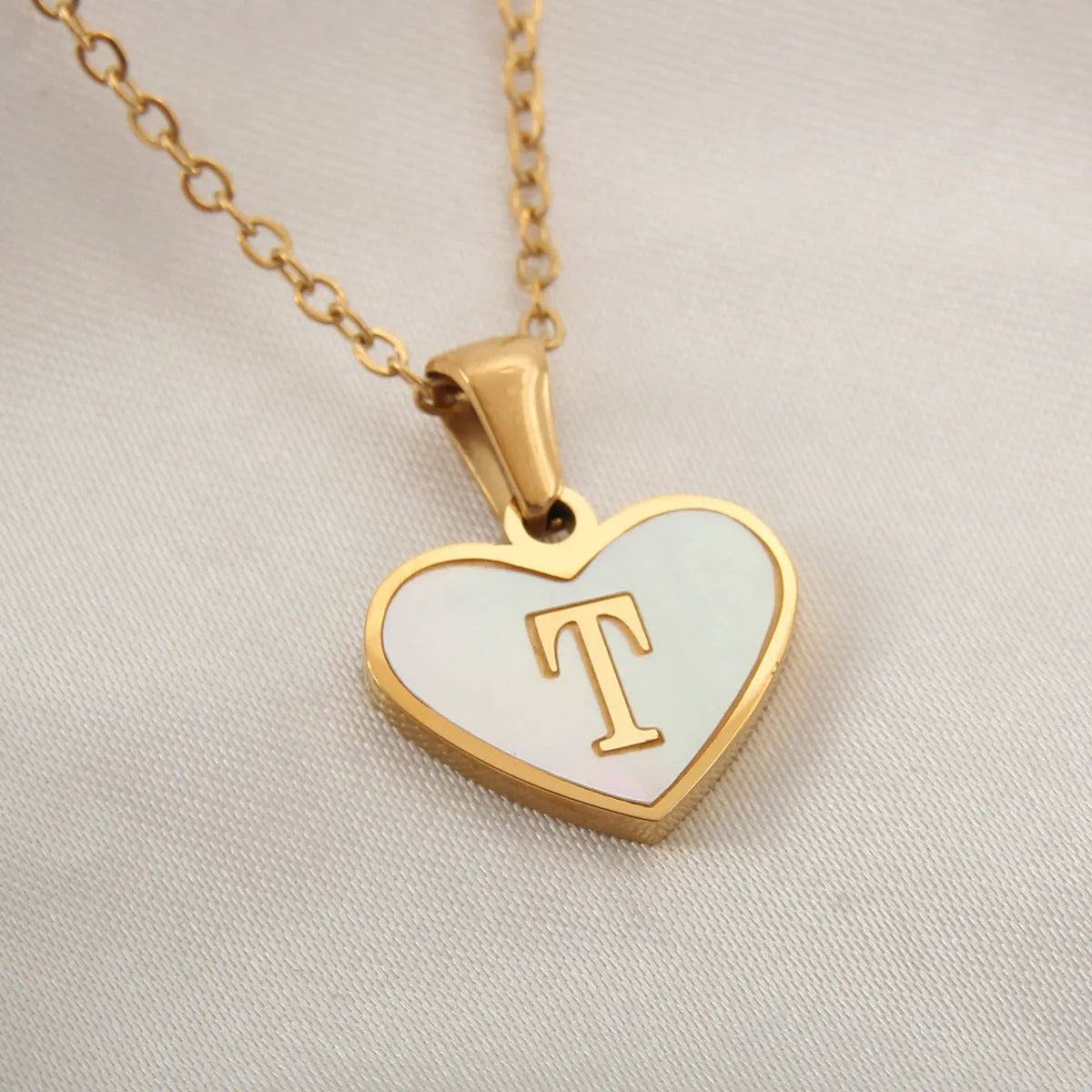 Gold-plated heart necklace with white shell pendant personalised with a letter, on an adjustable chain.