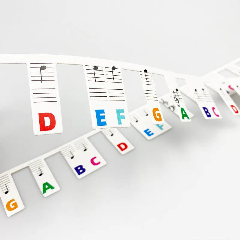 Two bags of white card piano keyboard stickers for 88 keys, showing colour note bar and black note designs.