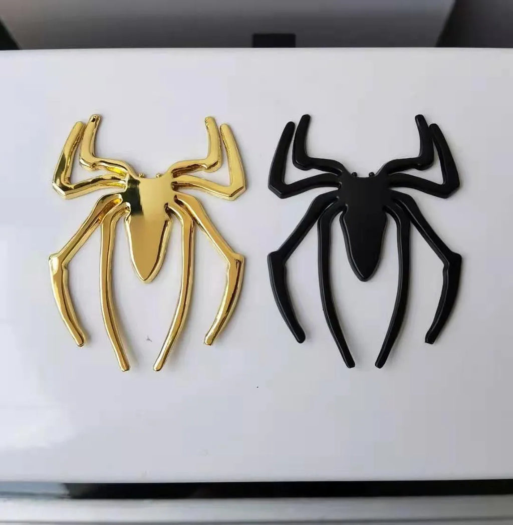 Three-dimensional metal spider-shaped bumper sticker in silver finish on a white background.