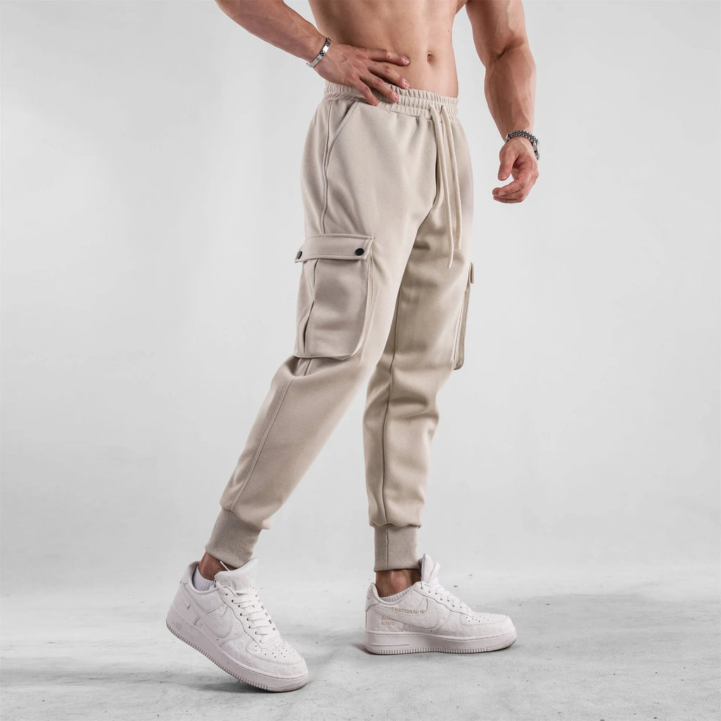 Man wearing loose light grey cotton trousers with ankle tie and multiple pockets, style of American sports leisure wear.