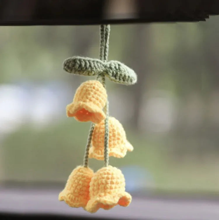 Green and white knitted wool car plant decoration with hanging rope on car dashboard