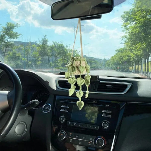Green and white knitted wool car plant decoration with hanging rope on car dashboard