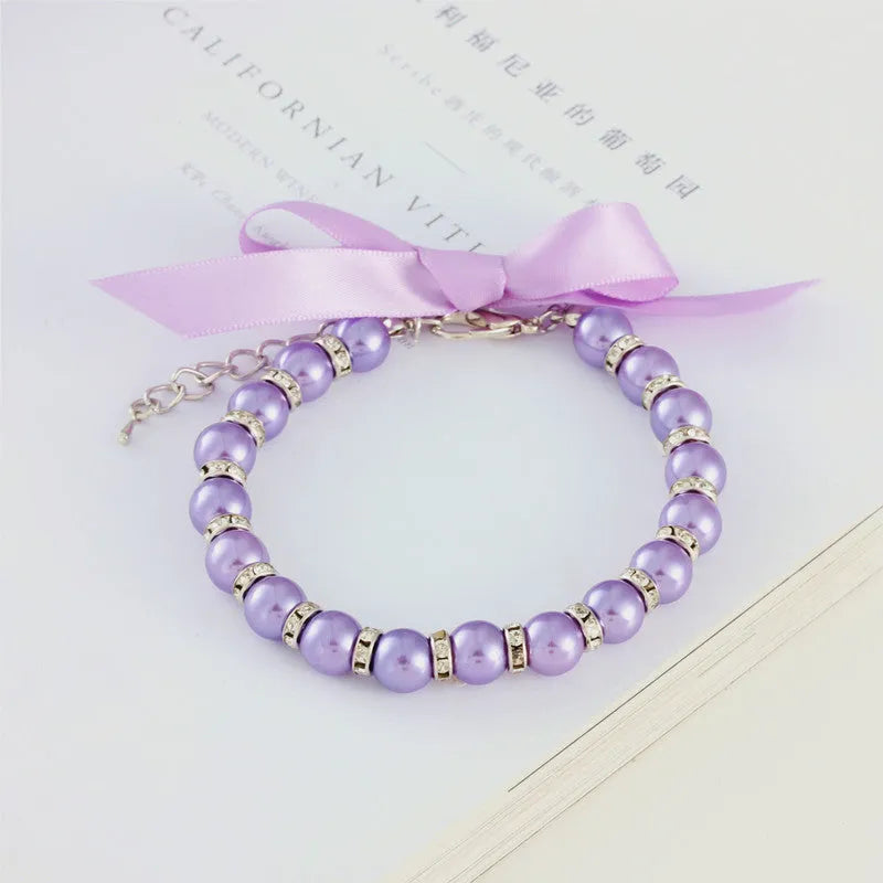Adjustable diamond dog pearl necklace with rhinestones and ribbon bow in blue, pink, purple, or white.