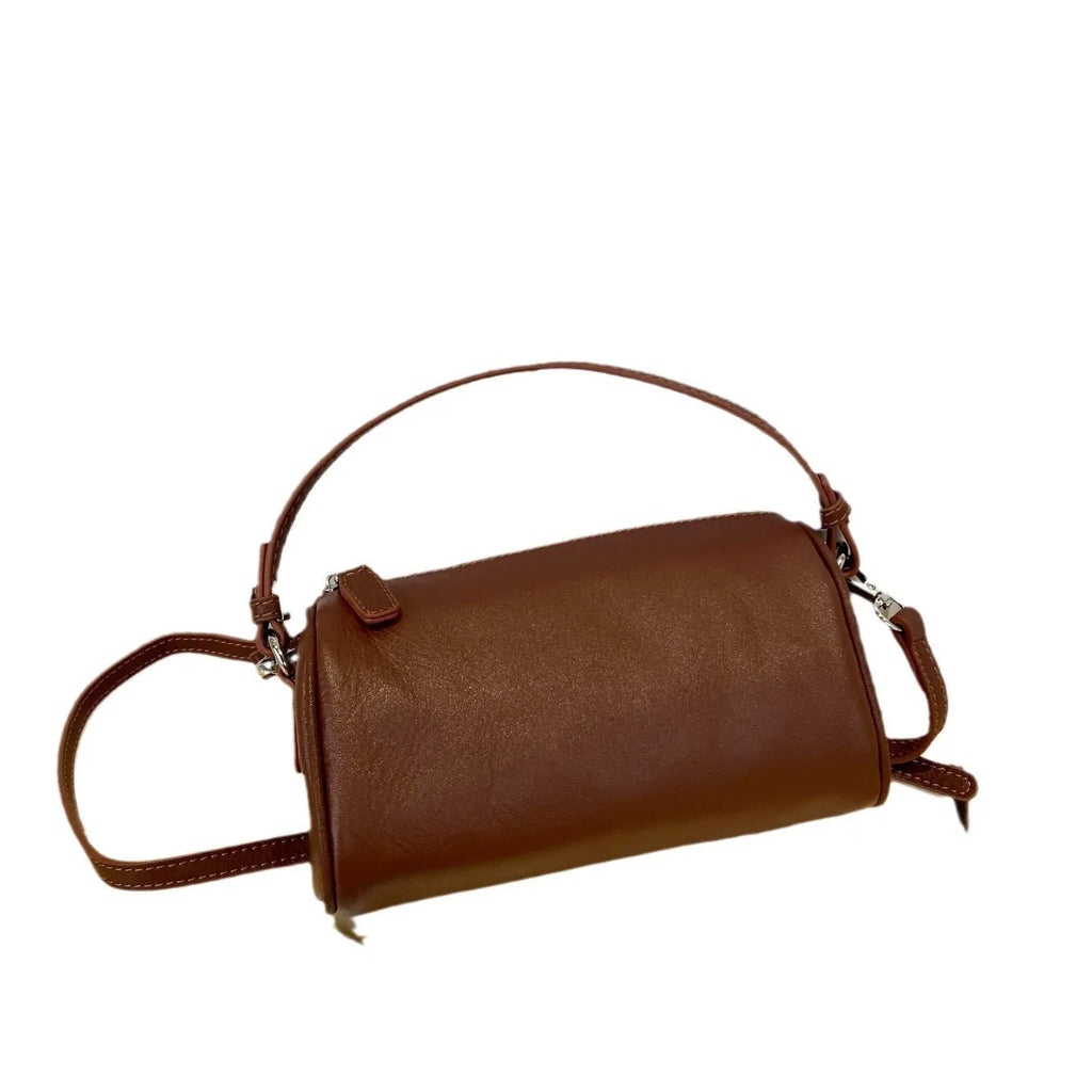 Soft genuine leather cylindrical crossbody bag for mobile phones, shown in a street style with visible stitching.