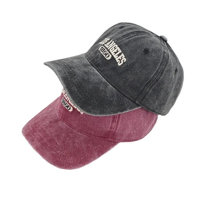 Retro washed distressed embroidered peaked cap with adjustable strap on a conical crown.