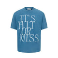 Man wearing a blue loose-fit T-shirt with a large white American retro style letter print on the front.