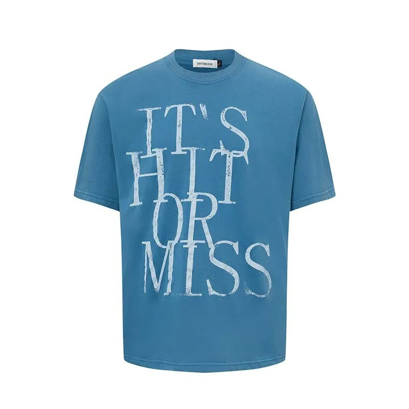 Man wearing a blue loose-fit T-shirt with a large white American retro style letter print on the front.
