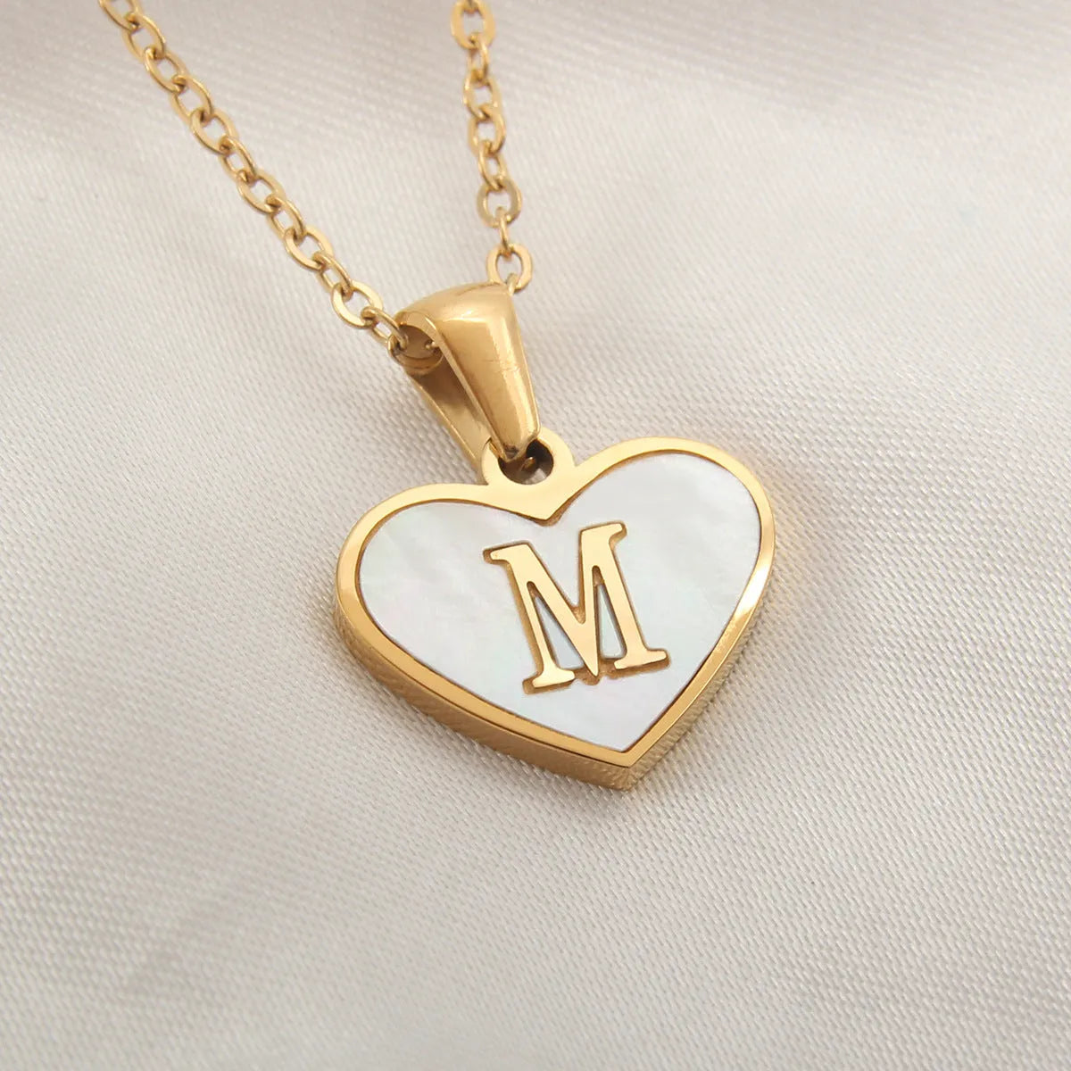 Gold-plated heart necklace with white shell pendant personalised with a letter, on an adjustable chain.