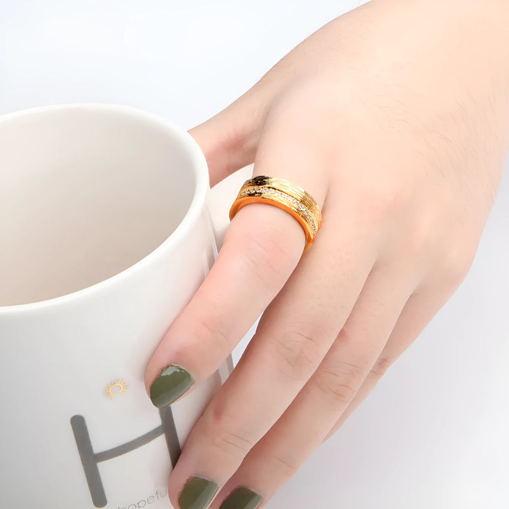 Gold coloured geometric zircon ring for women on a plain background, showing its structured shape.