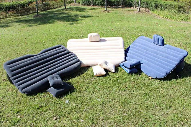 Inflatable car bed with flocked surface and two pillows, shown folded next to its storage bag.