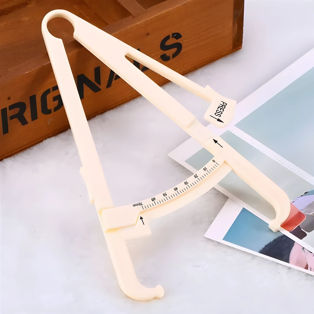 Transparent acrylic body fat caliper with measurement scale on a white background.