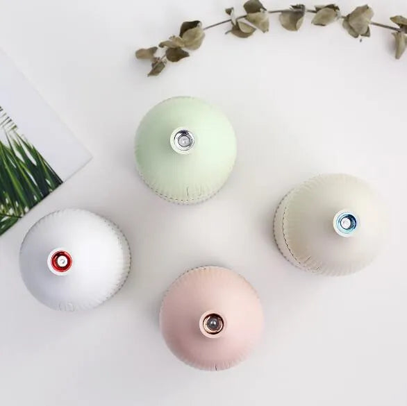 White ultrasonic aromatherapy diffuser and humidifier with LED light on a wooden surface.