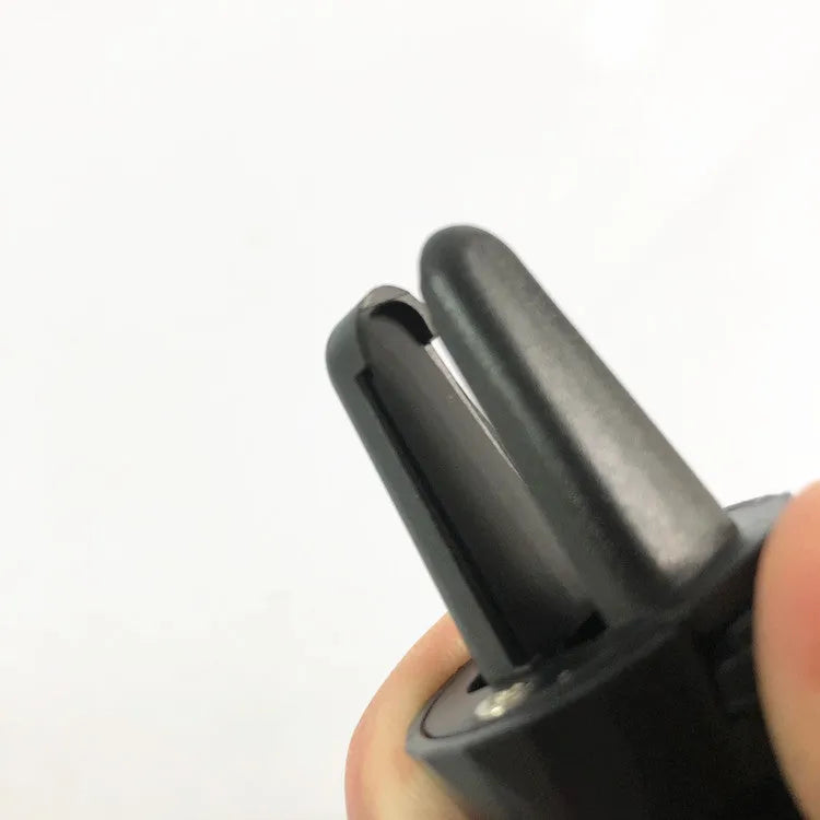 Black car phone holder attached to car air vent with adjustable arms holding mobile device