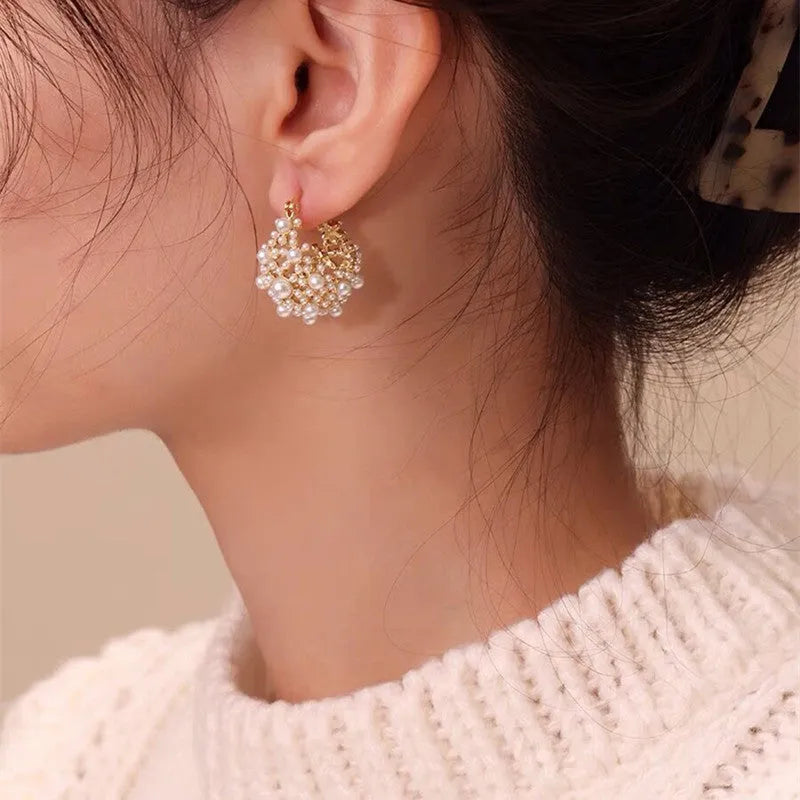 Gold-coloured copper flower basket earrings with small rice-shaped bead inlay detail.