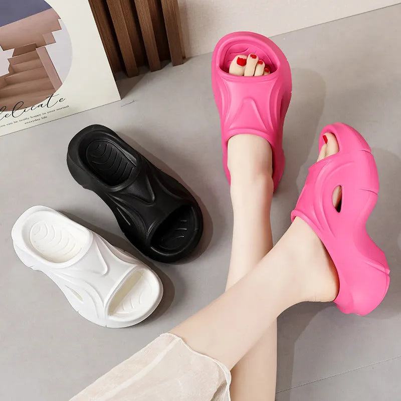 Women's thick-soled EVA slippers in rose red, shown on a beach background.