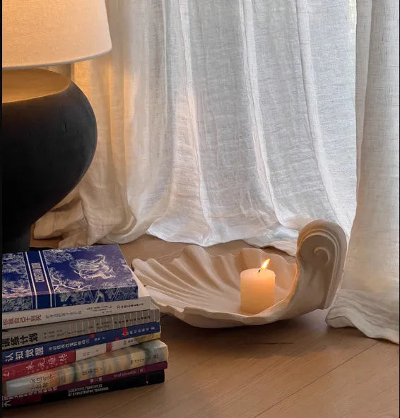 White resin shell-shaped fruit plate ornament on a table.
