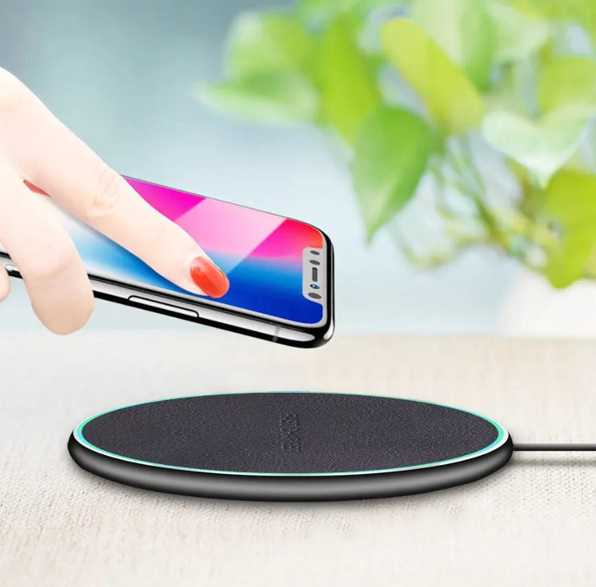 Black Quick Qi wireless charging pad for iPhone 11 on a desk surface