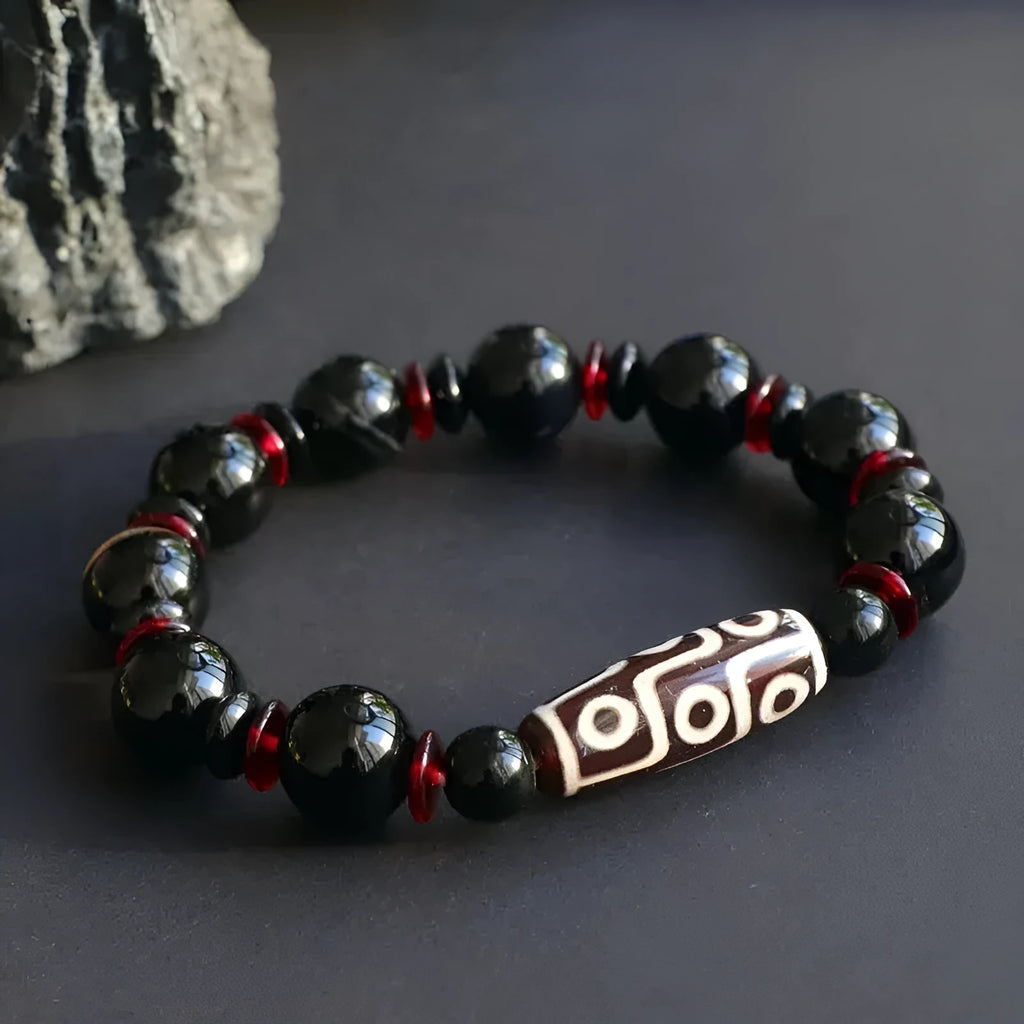 Close-up of a hand-woven black agate bracelet with 11mm geometric beads featuring traditional dzi patterns.