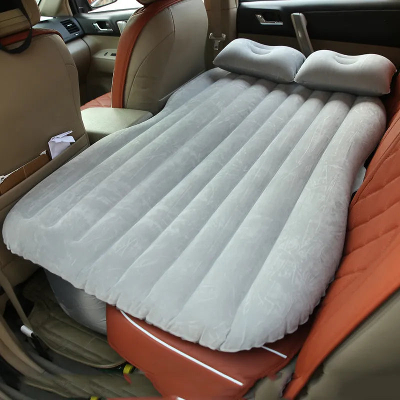 Inflatable car bed with flocked surface and two pillows, shown folded next to its storage bag.