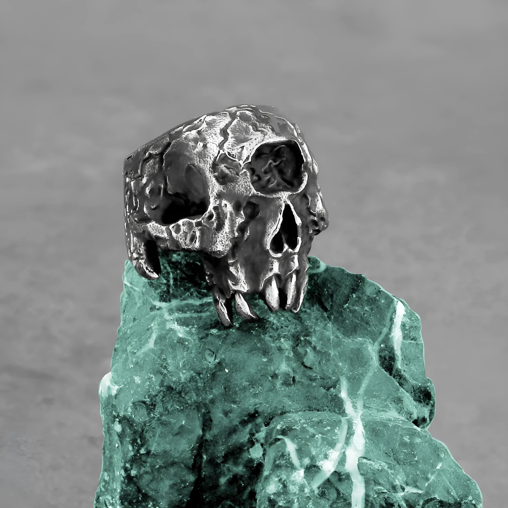 Close-up of a silver-toned alloy ring with a detailed one-eyed skull design on the finger.