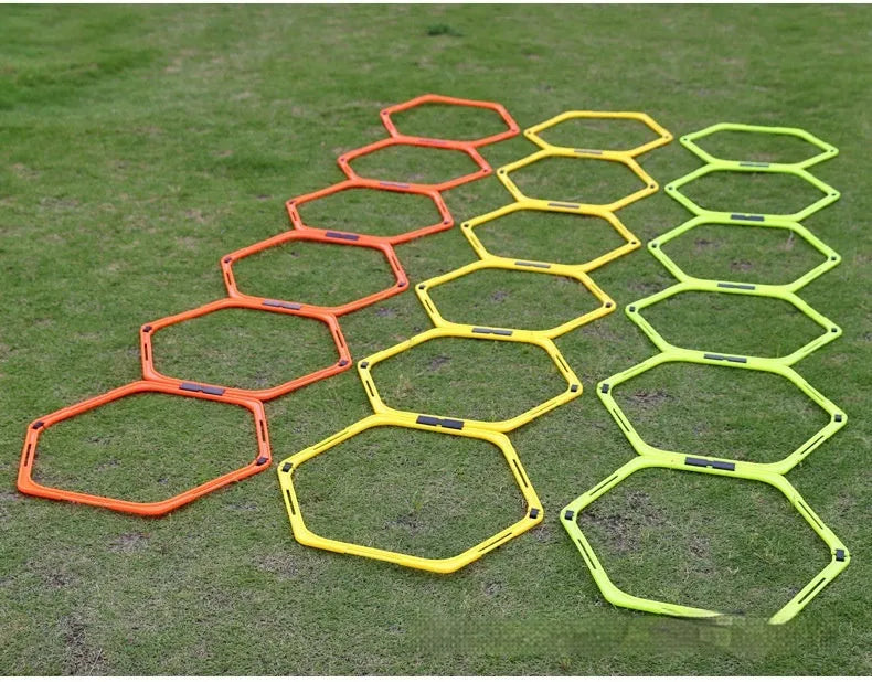 Six foldable yellow, green, and orange hexagon football agility training rings laid out on grass.