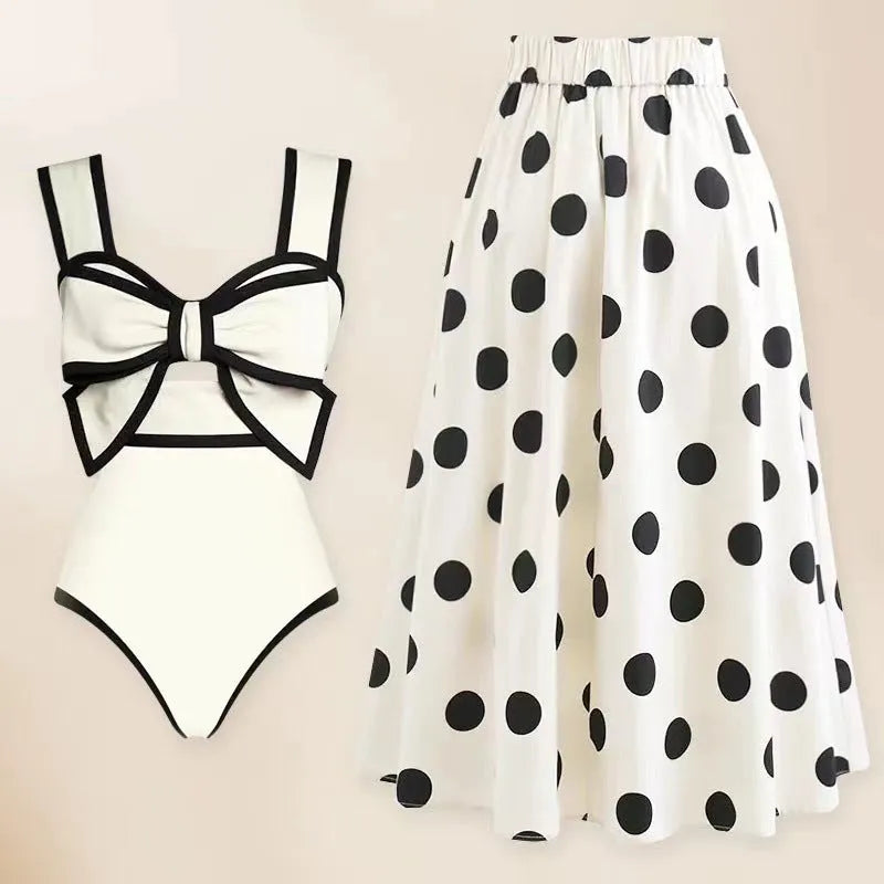Women's black one-piece swimsuit with a white bow-accented beach dress cover-up skirt.