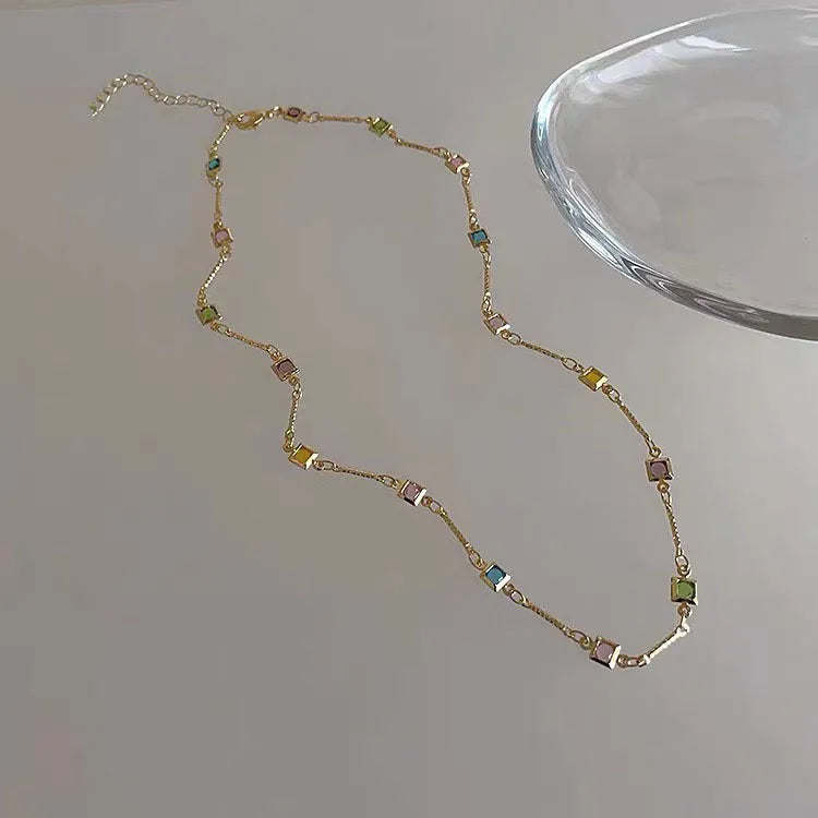 Square artificial crystal pendant on a fine gold clavicle chain necklace.