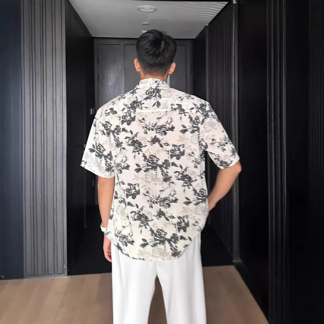 Man wearing a loose black floral print short sleeve casual shirt with a cardigan style open front.