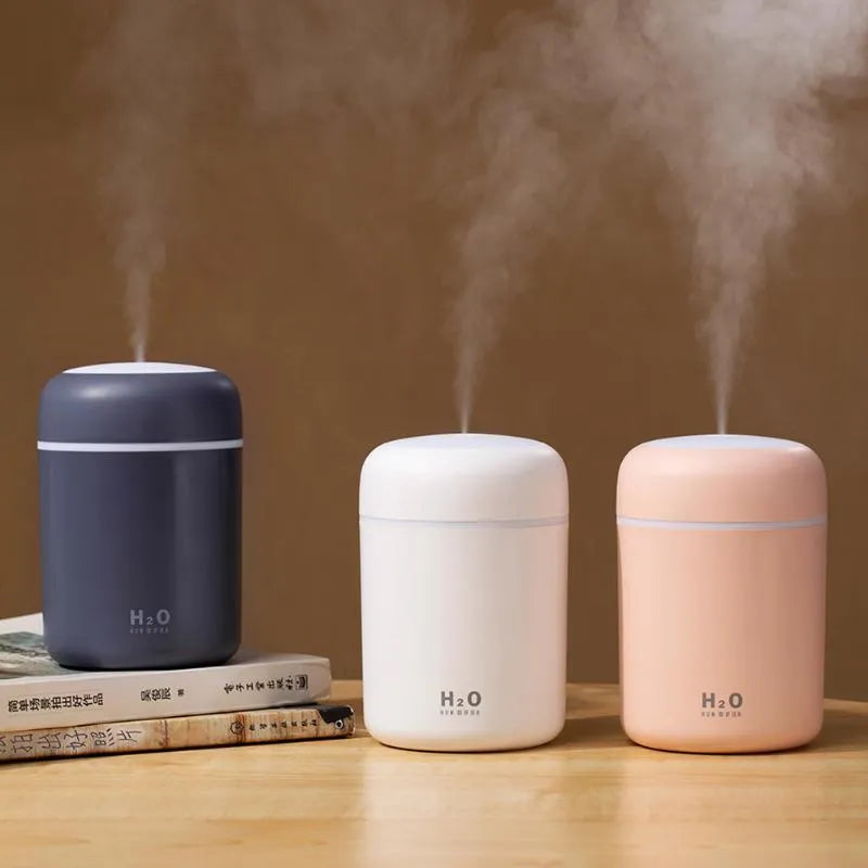 Pink USB mini humidifier with LED lights and water tank on desk