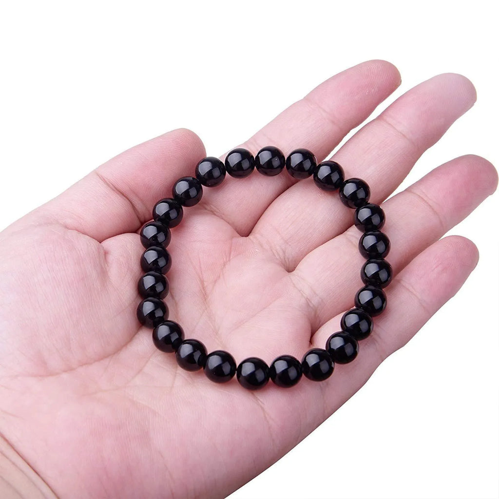 A geometric black onyx bracelet for women with 8mm beads on an elastic cord.