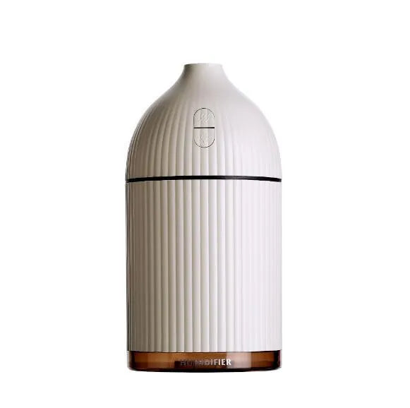White ultrasonic aromatherapy diffuser and humidifier with LED light on a wooden surface.